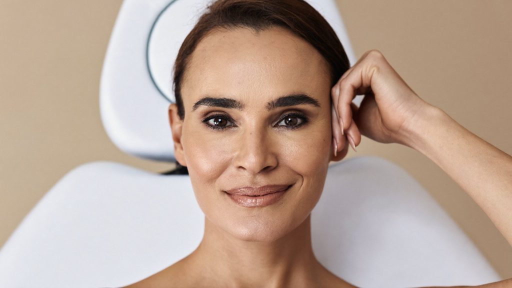Woman in her 50s with a defined jawline and healthy skin in a premium aesthetics clinic