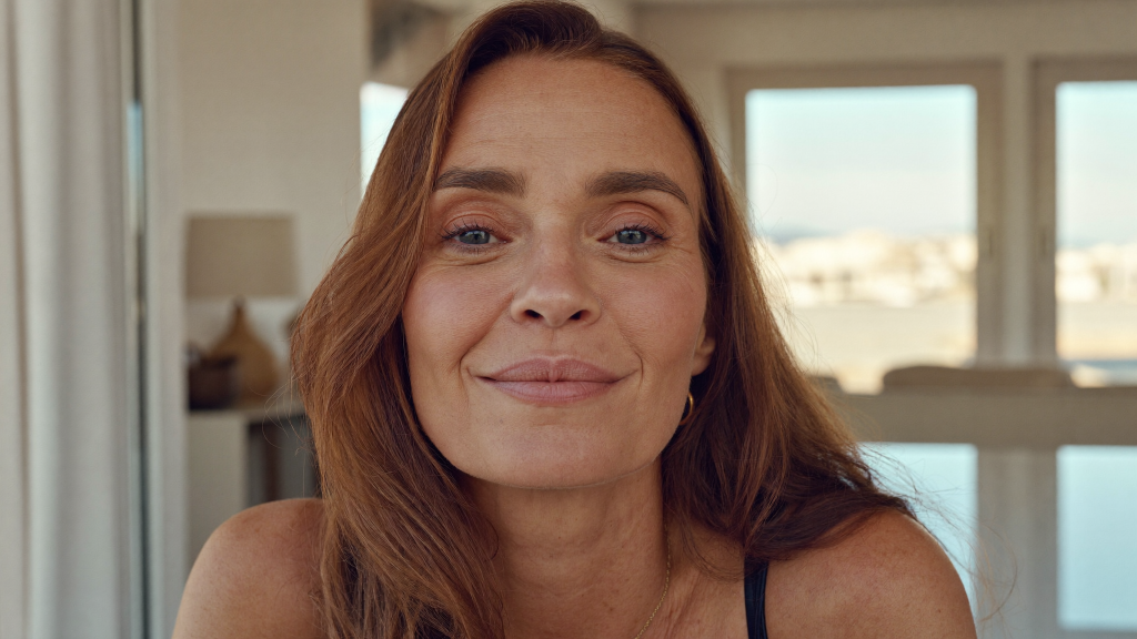 Woman in her late forties by a window showing natural nasolabial folds and healthy skin